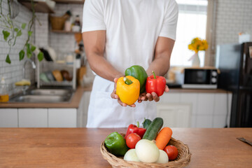Obraz na płótnie Canvas Man holding bell pepper preparing food in kitchen at home.