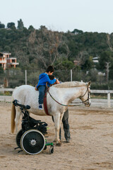 Boy with disabilities embracing his equine therapy instructor at equestrian center.