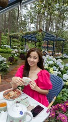 a beautiful woman wearing pink dress was sitting on dining table and having breakfast