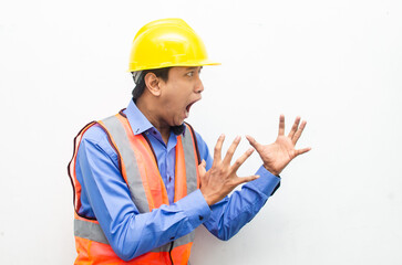 side view of stressed over work concept illustrated by asian male construction worker in blue shirt, orange vest and yellow safety helmet with furious, mad, sad, angry expression. overworked concept