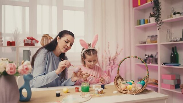 Mom and daughter having fun when decorating Easter eggs, bonding relationship