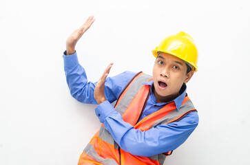 asian construction worker wearing yellow safety helmet and vest smiling and pointing finger with happy and shocked expression. billboard model advertisment concept. 