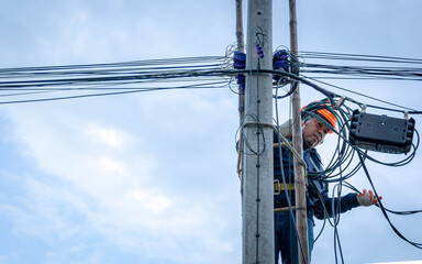 A technician working on ladder carefully for maintenance fiber optic wires attached to electric...