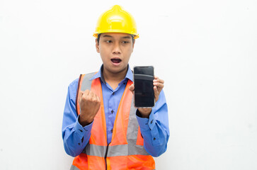 attractive young Asian male construction worker or engineer wearing an orange safety vest and a yellow hardhat holding a phone with shocked, surprised, and amazed expressions. 