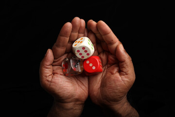 Asian dark skin top view two hand finger holding playing dice gamble luck on black background