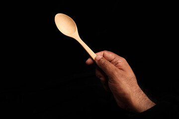 Asian dark skin top view two hand finger holding empty wooden spoon on black background