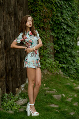 Beautiful fashionable woman outdoors. Young female model wearing dress posing in summer park.