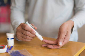 young man using blood test kit at home while doing health check . home finger prick blood test . close up, diabetes concept, elderly health care,