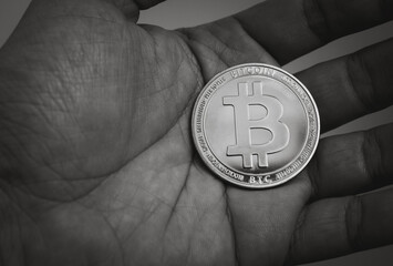 black and white bitcoin on hand in close up, concept of investment in cryptocurrency