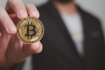 golden bitcoin holding by hand of businessman, concept of cryptocurrency and future investment and economy