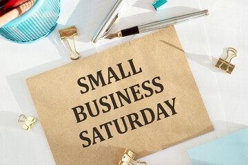 Text Small Business Saturday on envelope on white table with office tools