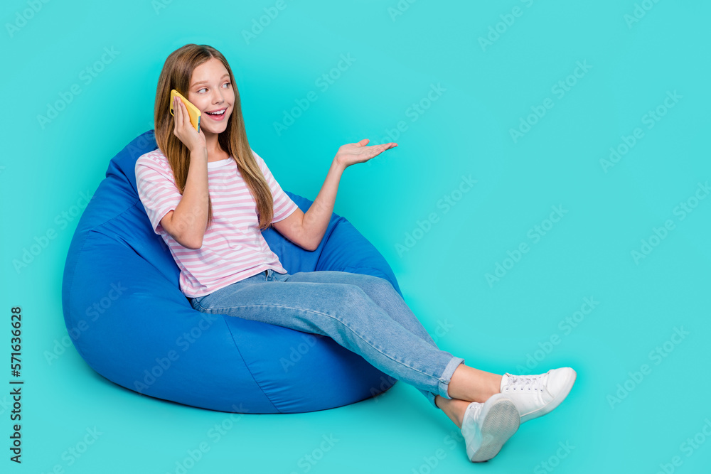 Poster full length photo of cute funny lady wear t-shirt sitting bean bag talking device empty space isolat