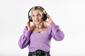 Young woman smiling confident wearing ribbed blouse standing isolated over white background touching headset, looks at the empty copy space and very happy. Smiling, looks at the advertising space.