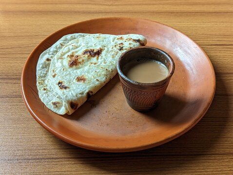 Chai Paratha on wooden background - Hot Tea served with Flatbread is a traditional simple meal from India and Pakistan