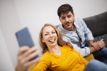 couple in love taking selfie smiling and having fun at home. girlfriend fooling around