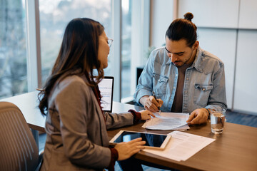 Happy candidate signing contract during job interview in office.