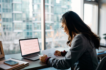 Asian businesswoman analyzing paperwork while working in office.