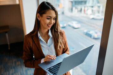 Young happy businesswoman working on laptop in office.