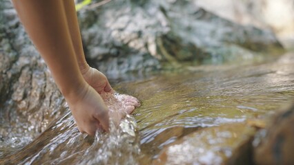 Hand scooping fresh stream water in the forest river or waterfall. Holding pure stream water in cupped hand