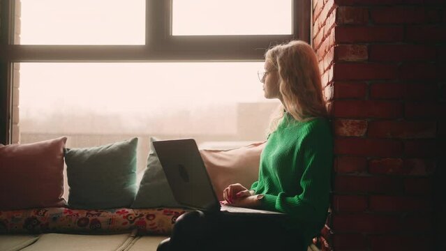 Overworked Freelancer Sitting On Windowsill Of Cafe And Working, Designer And It Specialist, Looking At Display And Waiting Answer In Work Chat