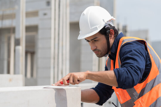 Foreman builder inspecting precast concrete wall structure quality at construction site. Construction worker wear safety uniform and helmet working with equipment tools at construction site