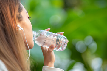 Asian woman drink clean fresh cold water from drinking plastic bottle. Drinking mineral water from bottle in hold hand and show.