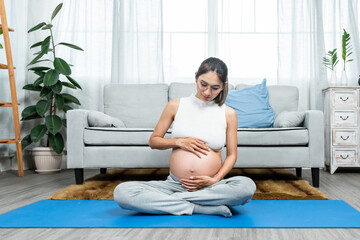 Close Up pregnant and very pregnant Asian mother ready to give birth to her baby. take both hands Wrap your belly with love. and wait for the day when he will be born. sitting on a yoga shirt