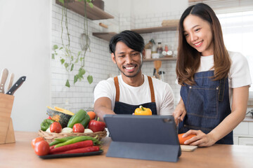 Romantic couple is cooking on kitchen. Handsome man and attractive young woman are having fun together while making salad. Healthy lifestyle concept.