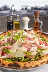 Classic Italian pizza with arugula and prosciutto, Mediterranean pizza with served table