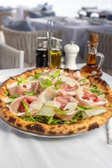 Classic Italian pizza with arugula and prosciutto, Mediterranean pizza with served table