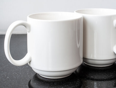 Two White Conference Coffee Mugs Standing Next To Each Other