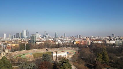 EUROPE, ITALY MILAN 2023 - Drone aerial view  in Sempione park - Arena old soccer Stadium  and the new skyline of the city in downtown - Old architecture and new modern skyscrapers in Gae Aulenti 