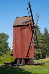 And old red windmill with wooden blades against a bright blue sky