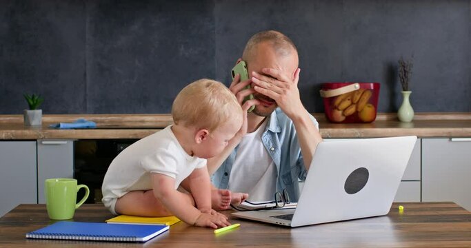 Dad of a little kid is trying to work on a laptop, the baby is crying and dad is nervous. Man's work on maternity leave.