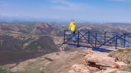 Kavkaz, Russia - May 31, 1922 - a young Russian woman admires the mountains, standing on a platform on the edge of a cliff