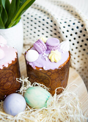 Colorful Easter eggs lie together with Easter pastries decorated with colored chocolate on a wooden table.