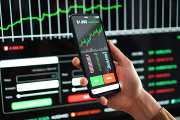 Crypto trader broker using a cell phone financial app to buy or sell shares of stock market....