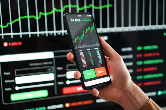 Crypto trader broker using a cell phone financial app to buy or sell shares of stock market. Investment concept. Caucasina hand holding a smartphone with banking blockchain application on the screen