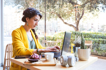 Woman in front of her laptop in front of a window of a cafeteria