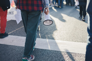 Teenage girl walking holding megaphone in her hands at a demonstration