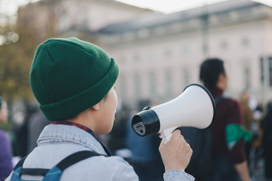 Teenage girl with green cap talking with megaphone in hand