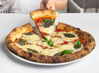 Man's hand holding a slice of Margherita pizza on a white background