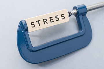 Stress concept. Wooden block with text on clamp