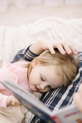 Cute little girl and her father. Father and little daughter spending weekend together at home, reading book in bed