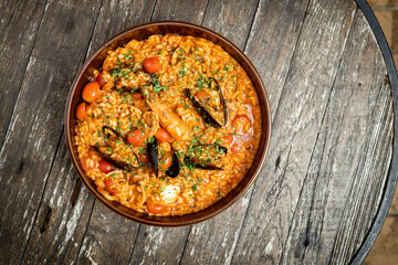 plate of risotto alla pescadora with seafood, on a rustic wooden background