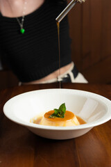 closeup milk pudding dessert, drizzled with whiskey, spoon and hand of the model in the photo, (selective focus)