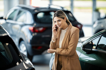 A customer support agent is standing at the car dealership salon and talking with customers.