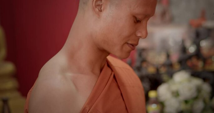 A slow-motion scene of a man who must be over twenty years old dressed in monk robes to prepare for ordination as a Buddhist monk.
