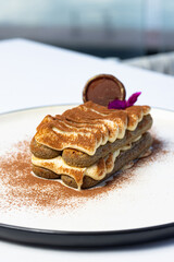 Classic Italian dessert Tiramisu on a white restaurant table against the background of the sea