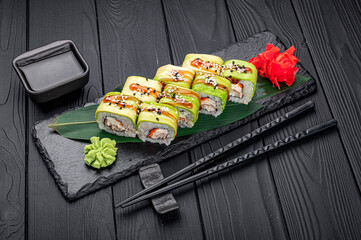 Sushi roll with smoked eel unagi covered by avocado and sesame seeds